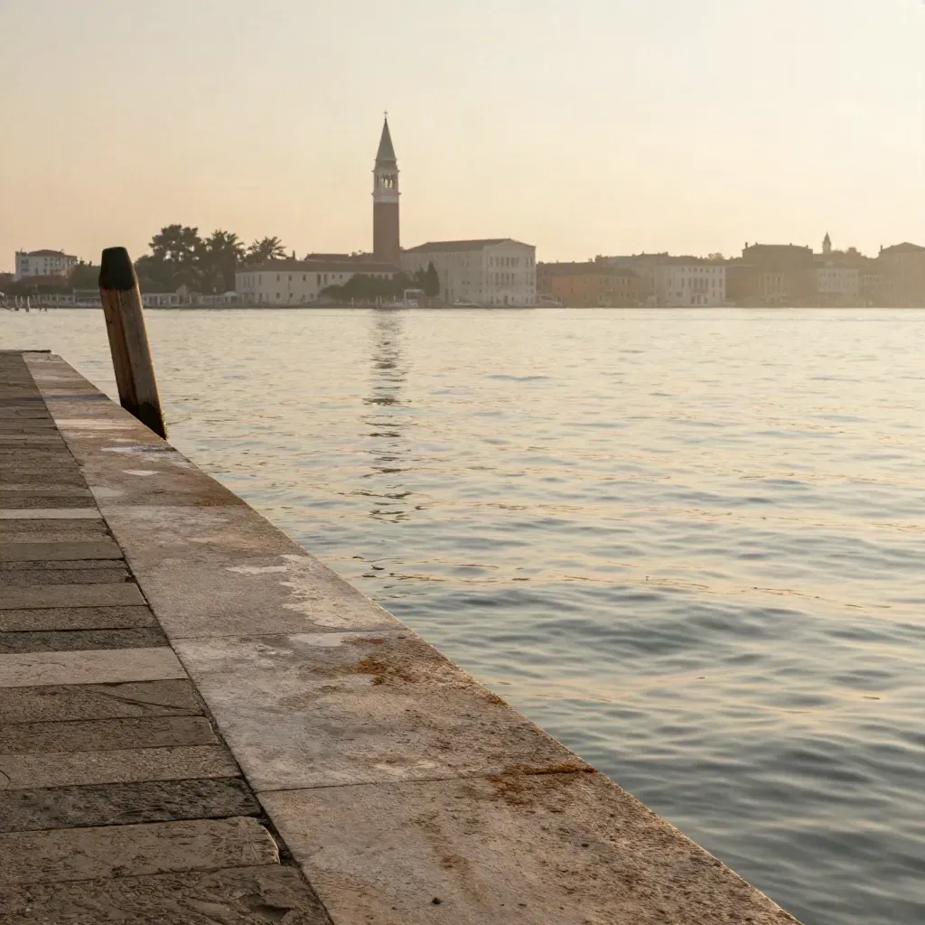 Riva veneziana in pietra con campanile lontano e laguna dorata nella foschia